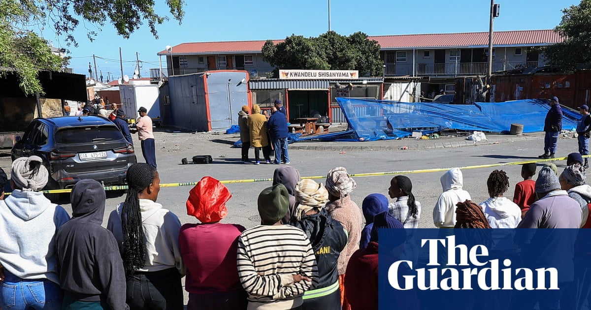 Locals look on behind police tape at one of the shooting scenes in South Africa.