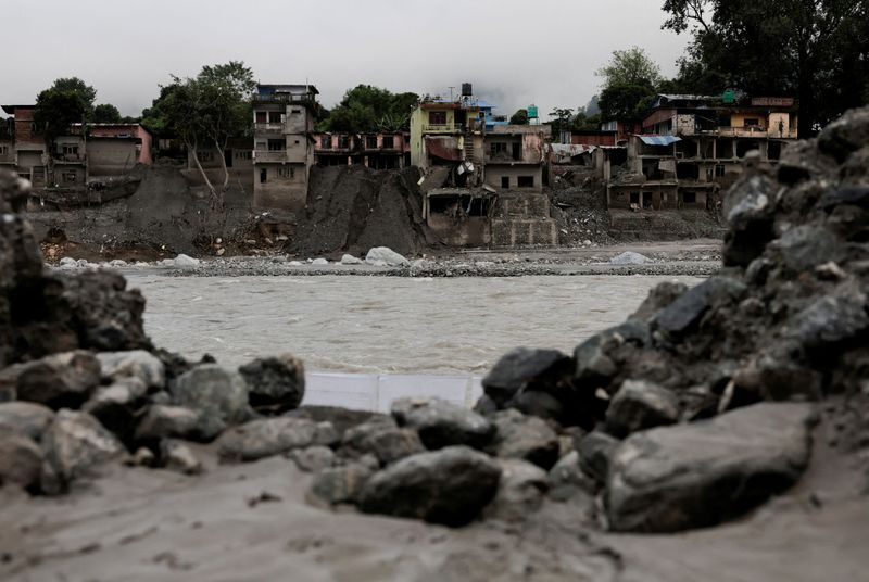 Damaged buildings and debris line a riverbank in Nepal following recent catastrophic outburst floods.
