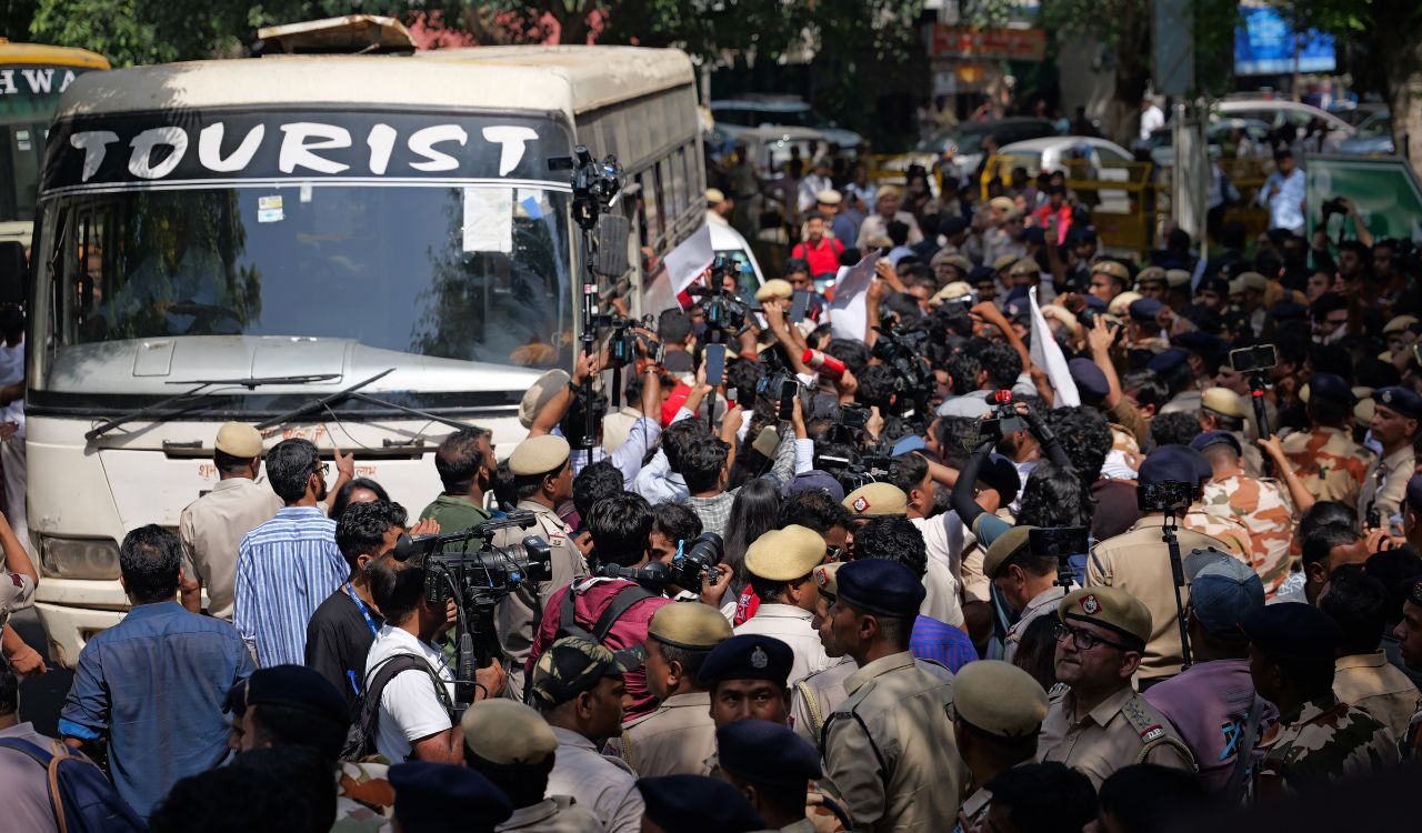 Security forces and media gather around a vehicle as protesters are detained during the demonstration in Delhi.